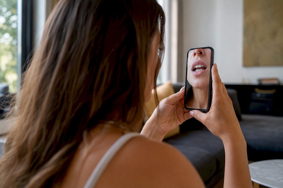 Patient photographing broken veneer in mirror at home